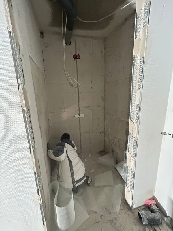 Ein Mann arbeitet in einem Badezimmer, das gerade renoviert wird.