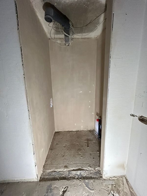 Ein leerer Raum mit einer Tür und einem Rohr, das aus der Decke kommt.