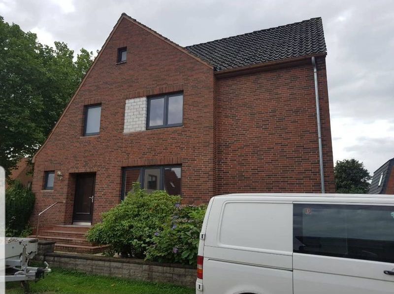 Ein weißer Lieferwagen steht vor einem großen Backsteinhaus