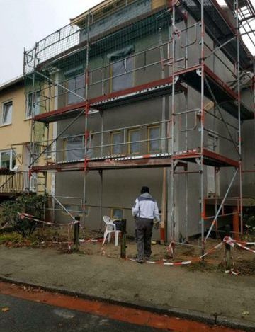 Ein Mann steht vor einem im Bau befindlichen Gebäude mit Gerüst.
