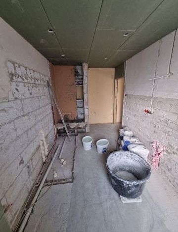 Ein Raum im Bau mit Eimern voller Zement auf dem Boden.