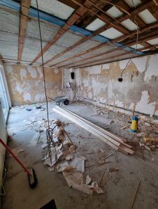 Ein Raum der mit Holzbalken und einem Besen umgestaltet wird.