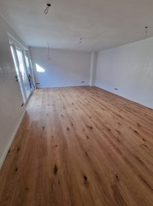 Ein großer leerer Raum mit Holzboden und weißen Wänden.