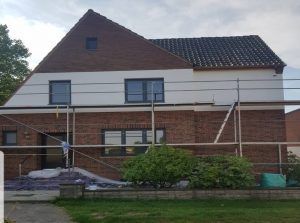 Ein Backsteinhaus mit Gerüst darum wird gestrichen.