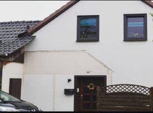 Ein weißes Haus, vor dem ein schwarzes Auto geparkt ist.