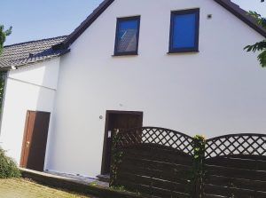 Ein weißes Haus mit einem Holzzaun davor.