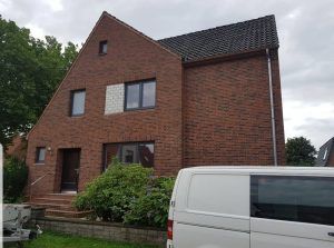 Ein weißer Lieferwagen parkt vor einem großen Backsteinhaus.