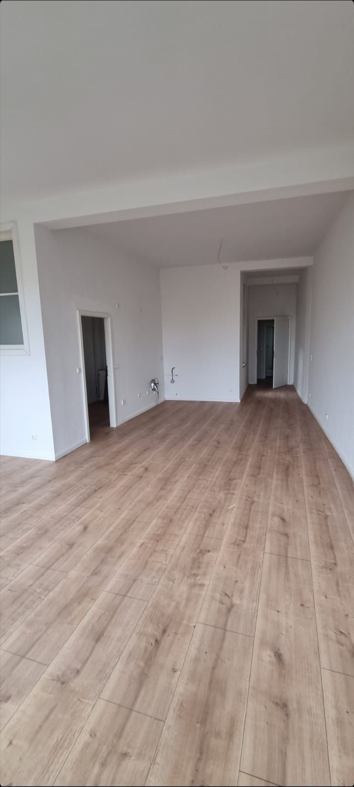 Ein großer leerer Raum mit Holzboden und weißen Wänden.