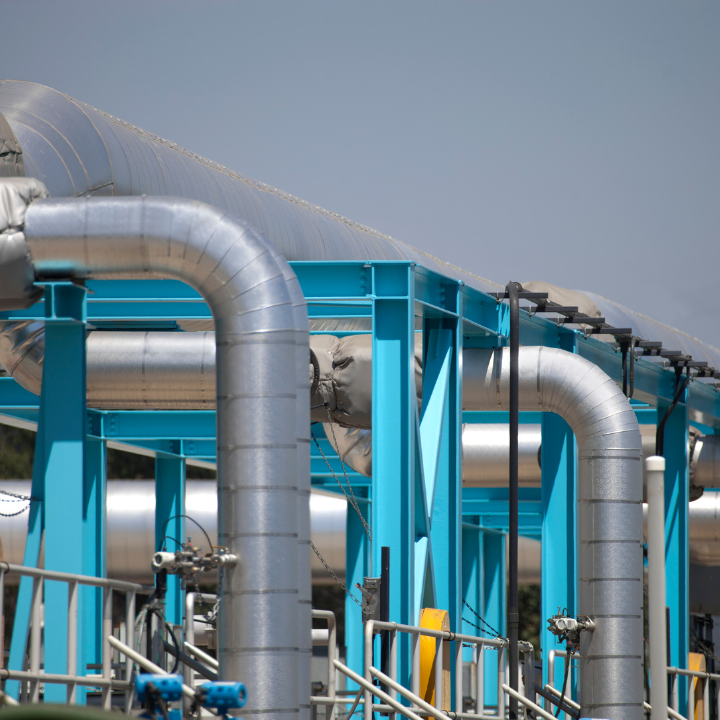 Estructura de soporte azul sostiene grandes tubos plateados, al aire libre.