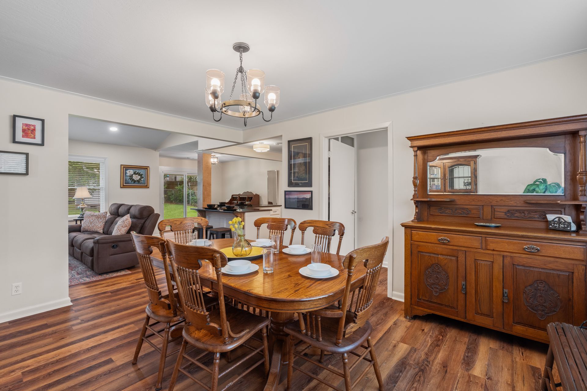 Dining room with wooden table, chairs, and buffet. Open to living room.