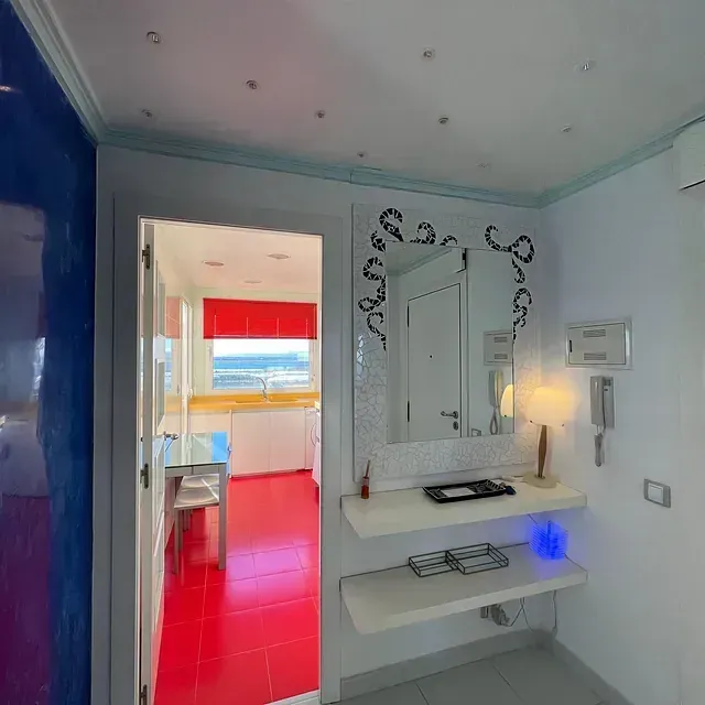 Una habitación con suelo rojo y un espejo en la pared.