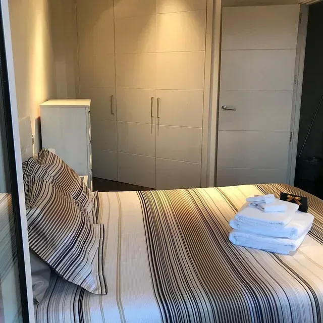 Un dormitorio con una cama y una pila de toallas encima.