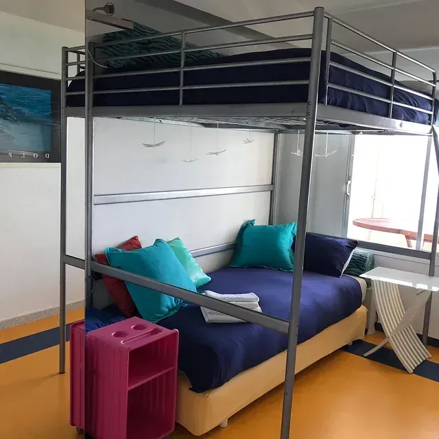 Una litera con sábanas moradas y almohadas azules