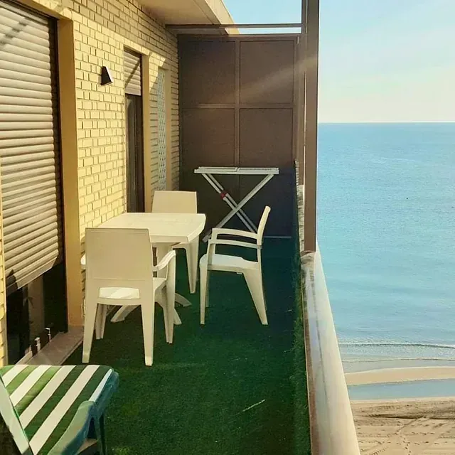 Un balcón con mesa y sillas con vista al mar.