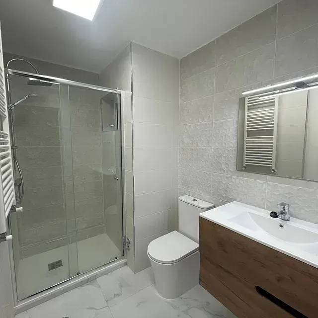 Un baño con inodoro, lavabo, ducha y espejo.