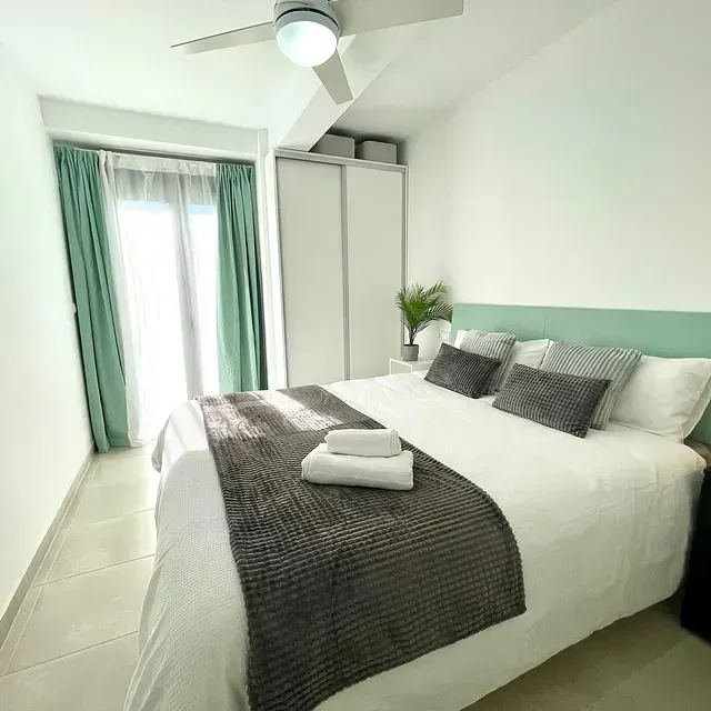 Un dormitorio con una cama grande y un ventilador de techo.