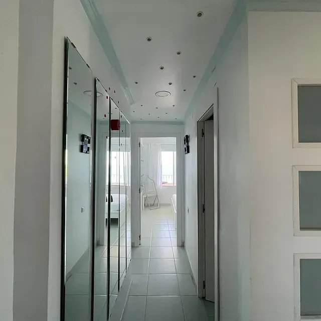 Un largo pasillo con espejos en la pared y el techo.