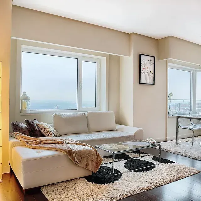 Una sala de estar con un sofá blanco y una mesa de centro de cristal.