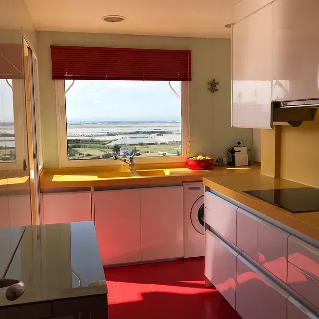 Una cocina con gabinetes blancos y una ventana grande.