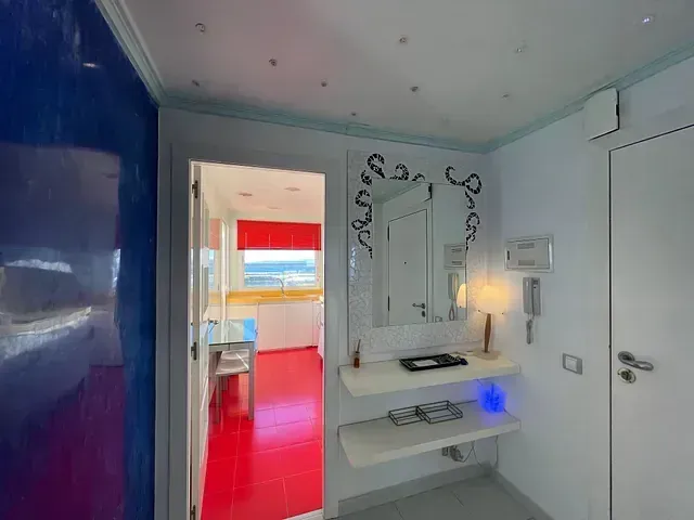 Un pasillo en una habitación de hotel con suelo rojo y un espejo.