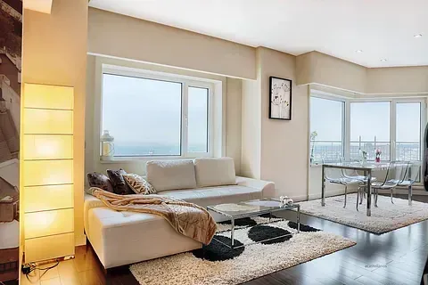 Una sala de estar con sofá, mesa, sillas y una gran ventana.