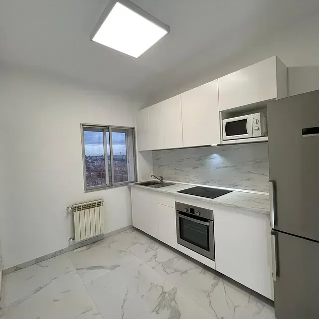 Una cocina con gabinetes blancos y un refrigerador de acero inoxidable.