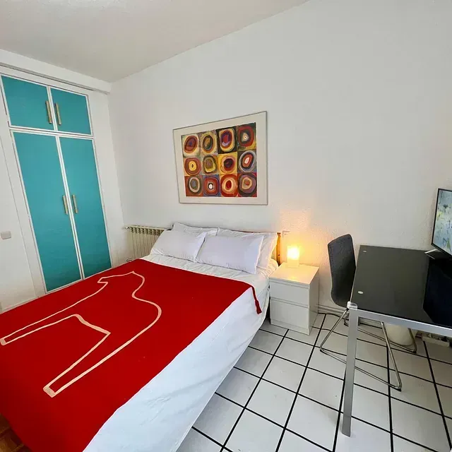 Un dormitorio con una manta roja sobre la cama.