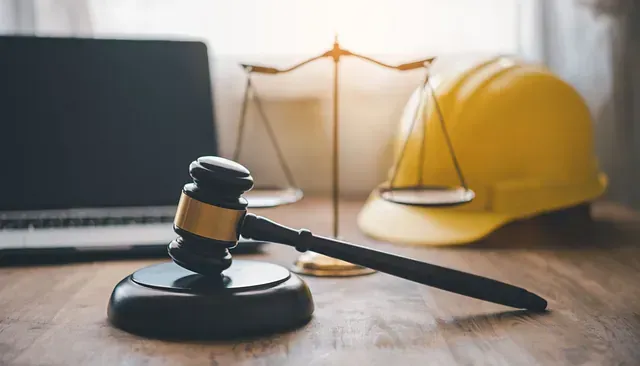 Un mazo de juez, una balanza de la justicia y un casco están sobre una mesa de madera.
