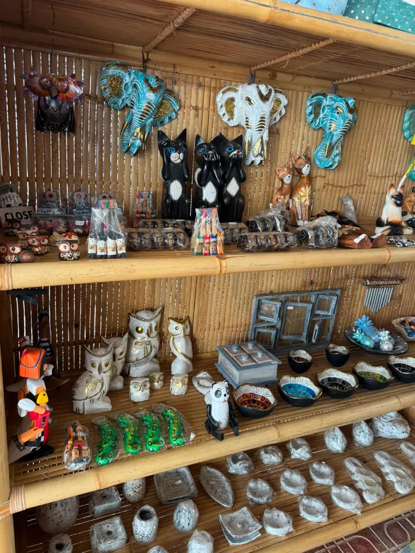 Figuritas de animales hechas a mano y pequeñas piezas de cerámica expuestas en estantes de bambú en una tienda rústica.
