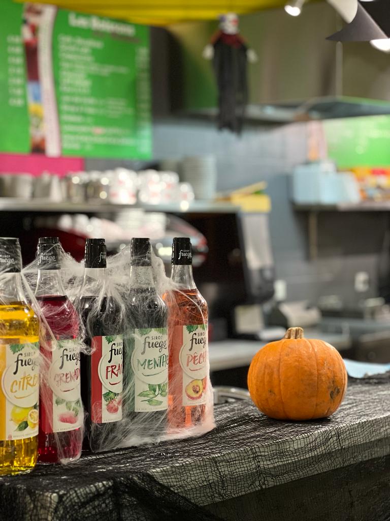 Des bouteilles de sirops et une citrouille sur le comptoir d'un restaurant.