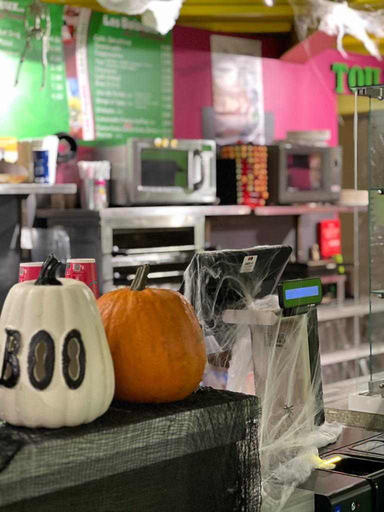 Deux citrouilles, une blanche avec l'inscription « BOO » et une orange, sur un comptoir.