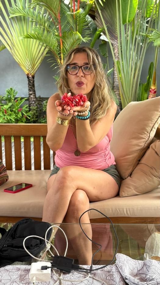 Mujer sosteniendo bayas rojas, sentada al aire libre, haciendo una cara de beso.