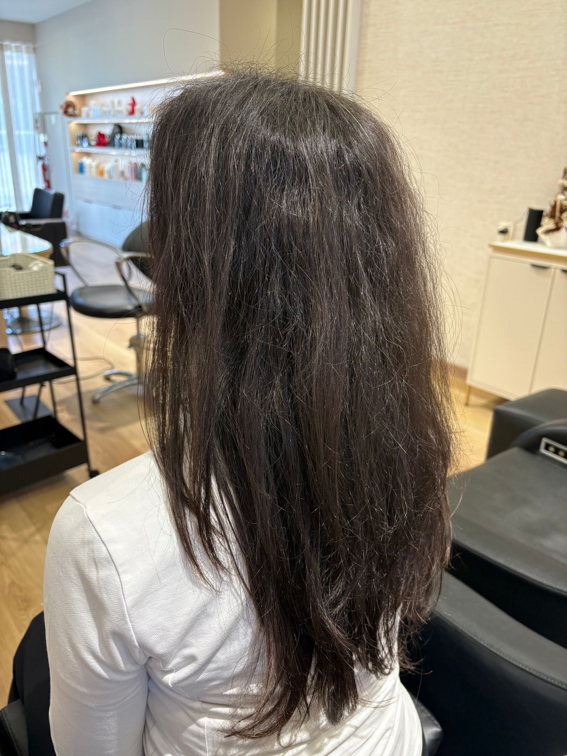 Cabelo castanho ondulado, provavelmente sem penteado, em um salão de beleza.