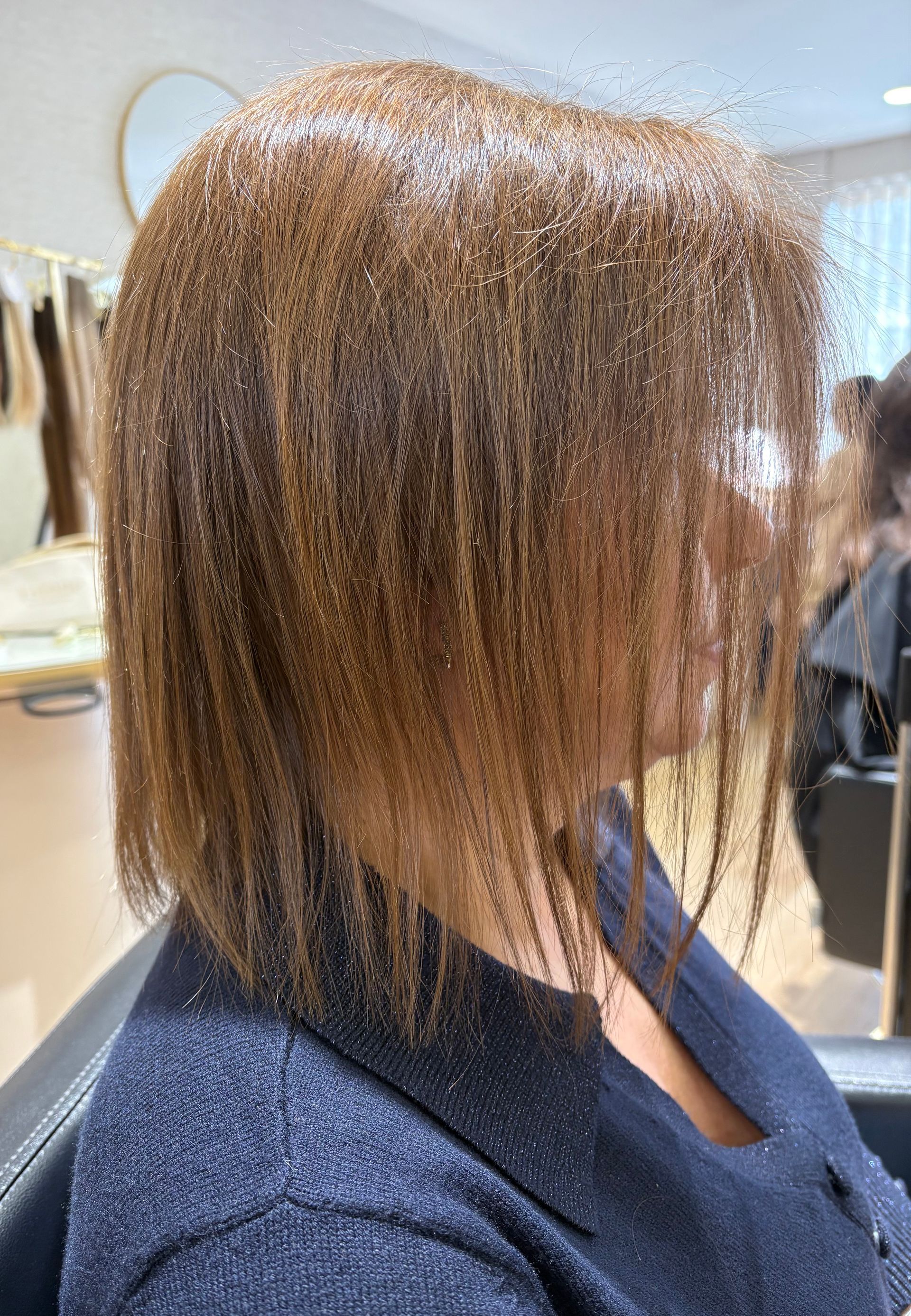 Pessoa com cabelo castanho comprido usando máscara, tendo o cabelo penteado por alguém que segura uma tesoura.