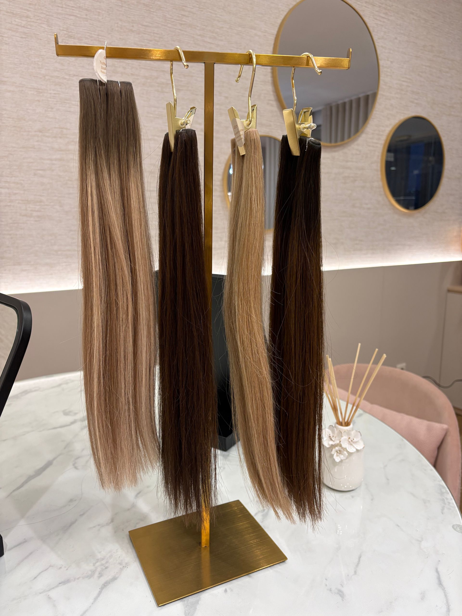 Frasco de perfume com tampa de madeira sobre uma bandeja dourada rodeada de folhagem.