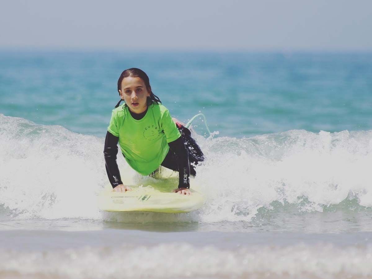 Un niño pequeño está montando una ola en una tabla de surf en el océano.
