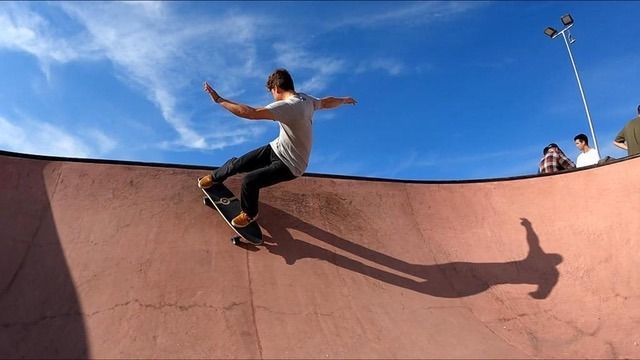 Un hombre va en patineta por una rampa en un parque de patinaje.