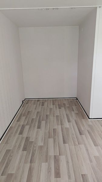 Tyhjä valkoinen vaatekaappi, jossa on puukuvioitu lattia ja avoin etuosa
