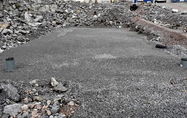Betonipolku kivisten rakennusmurskeiden läpi, pienet tolpat molemmin puolin.