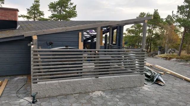 Moderni talon terassi, jossa on harmaa sälekaite ja katettu patio, ajotieltä päin katsottuna.