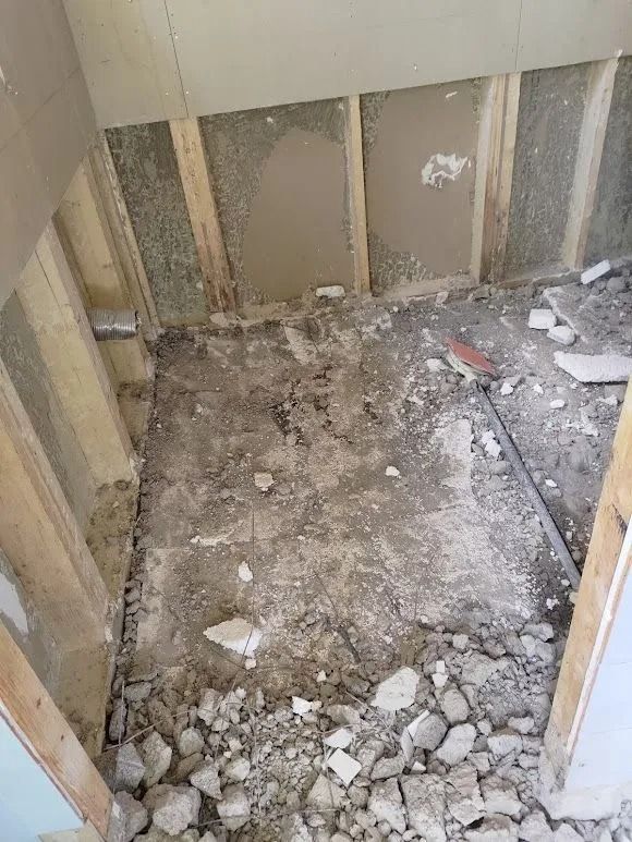 Osittain purettu huone, jossa on näkyvissä seinätukia, roskia ja rikkoutunutta betonia lattialla