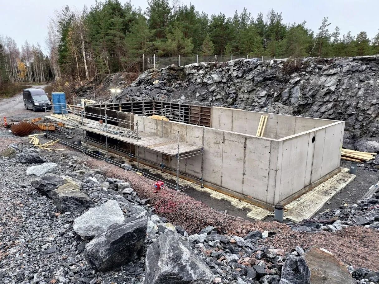 Betonirakenteinen perustus kallioisella paikalla metsäisen rinteen taustalla