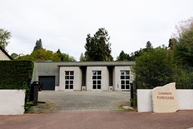 Petit cottage blanc au toit noir, entouré de haies et portant l'inscription « Clarke Pottery ».