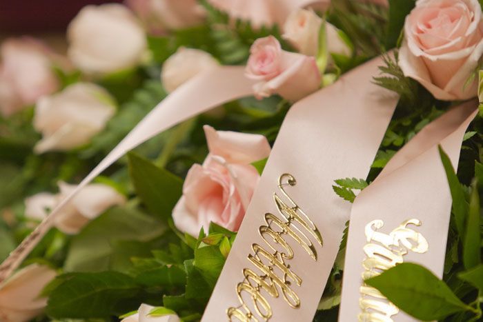 Des roses roses avec un ruban couleur crème ; l'inscription dorée dit  Avec toute ma sympathie.