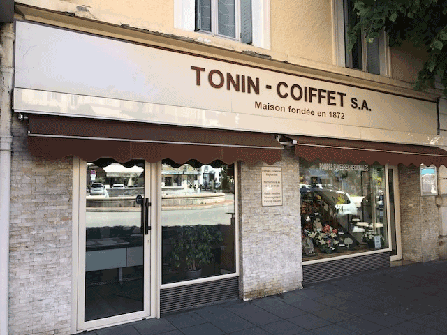 Façade de salon de coiffure avec auvent, enseigne TONIN - COIFFET SA au-dessus de l'entrée.