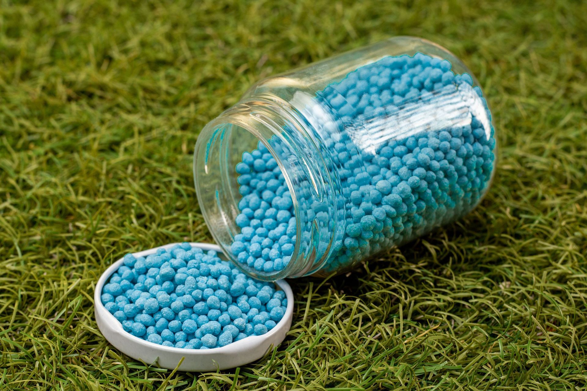 Un frasco de fertilizante azul se encuentra encima de un exuberante campo verde.