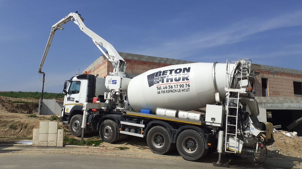 Une livraison de béton avec un camion-citerne blanc avec le logo de l'entreprise