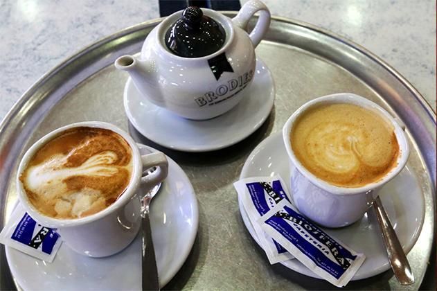 Tres tazas de café y una tetera en una bandeja de plata