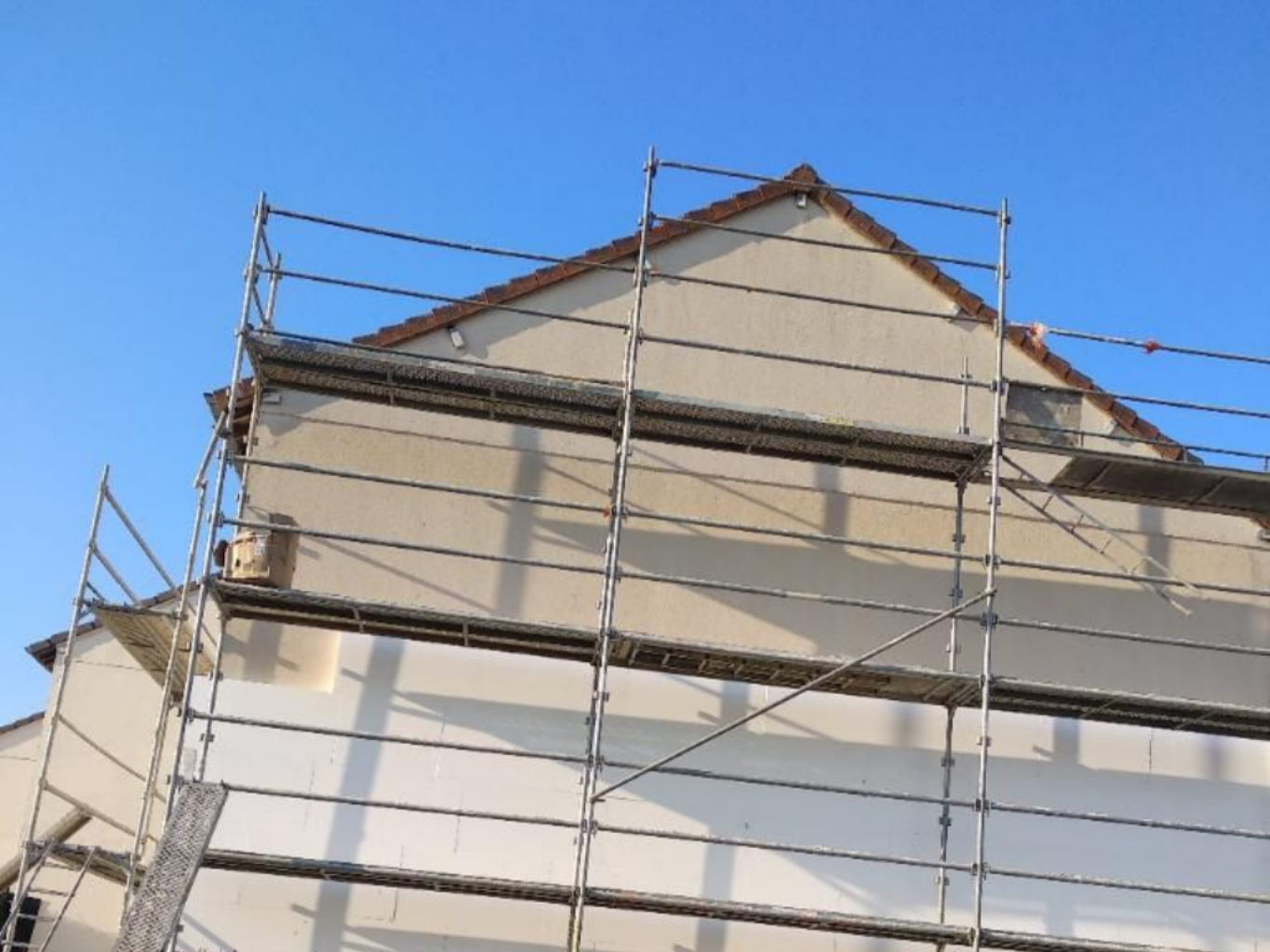 Extérieur d’une maison avec un échafaudage sous un ciel bleu
