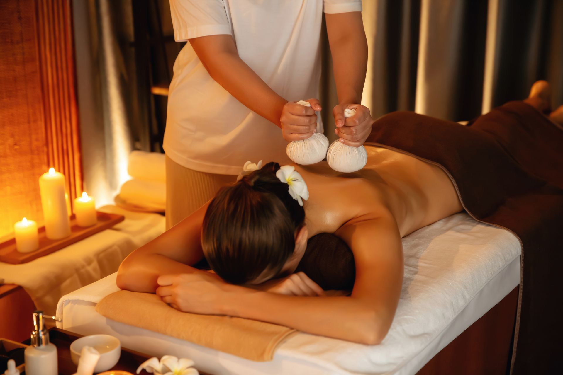 Massage avec des compresses chaudes dans une pièce avec des bougies